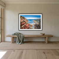 North Head Worang Point framed print in black with a white mat, above an oak bench in a hallway