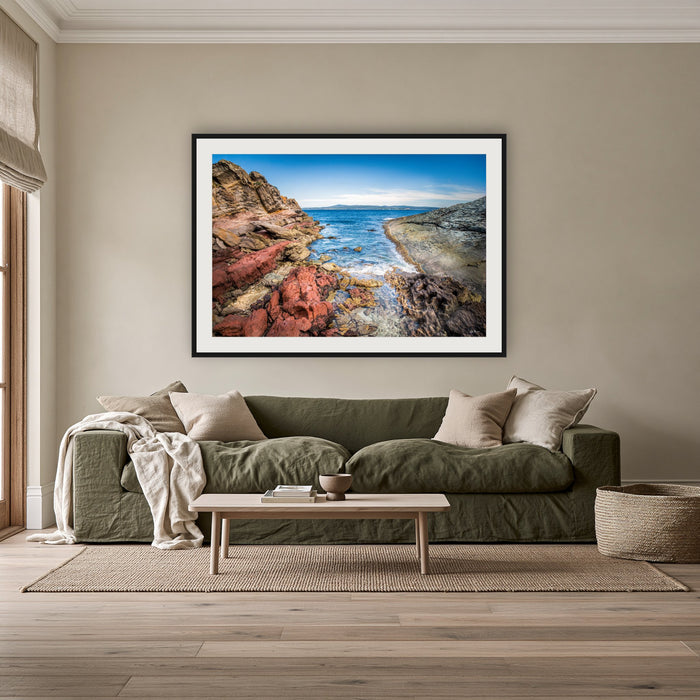 North Head Worang Point framed print in black with a white mat, above an olive linen sofa in a lounge room