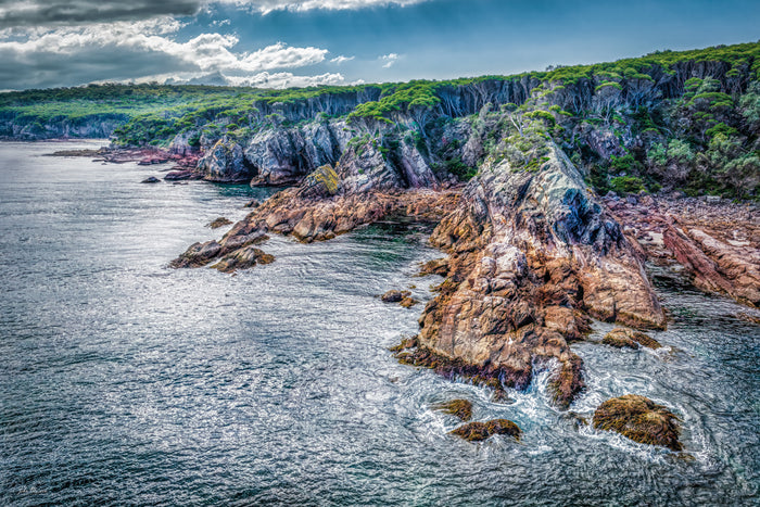 The rocky coastline and bush-topped cliffs at North Head from the air, surf breaking around the point — fine art print