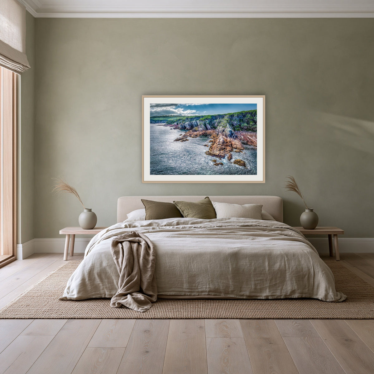 North Head Worang Point framed print in oak with a white mat, above a linen bed against a sage wall in a bedroom
