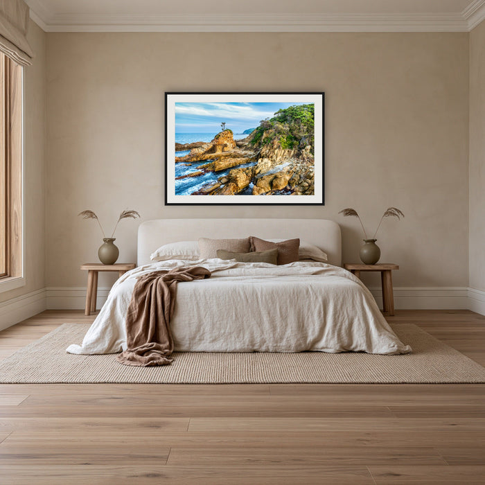 Lone Tree at Cuttagee framed print in black with a white mat, above an ivory linen bed in a bedroom