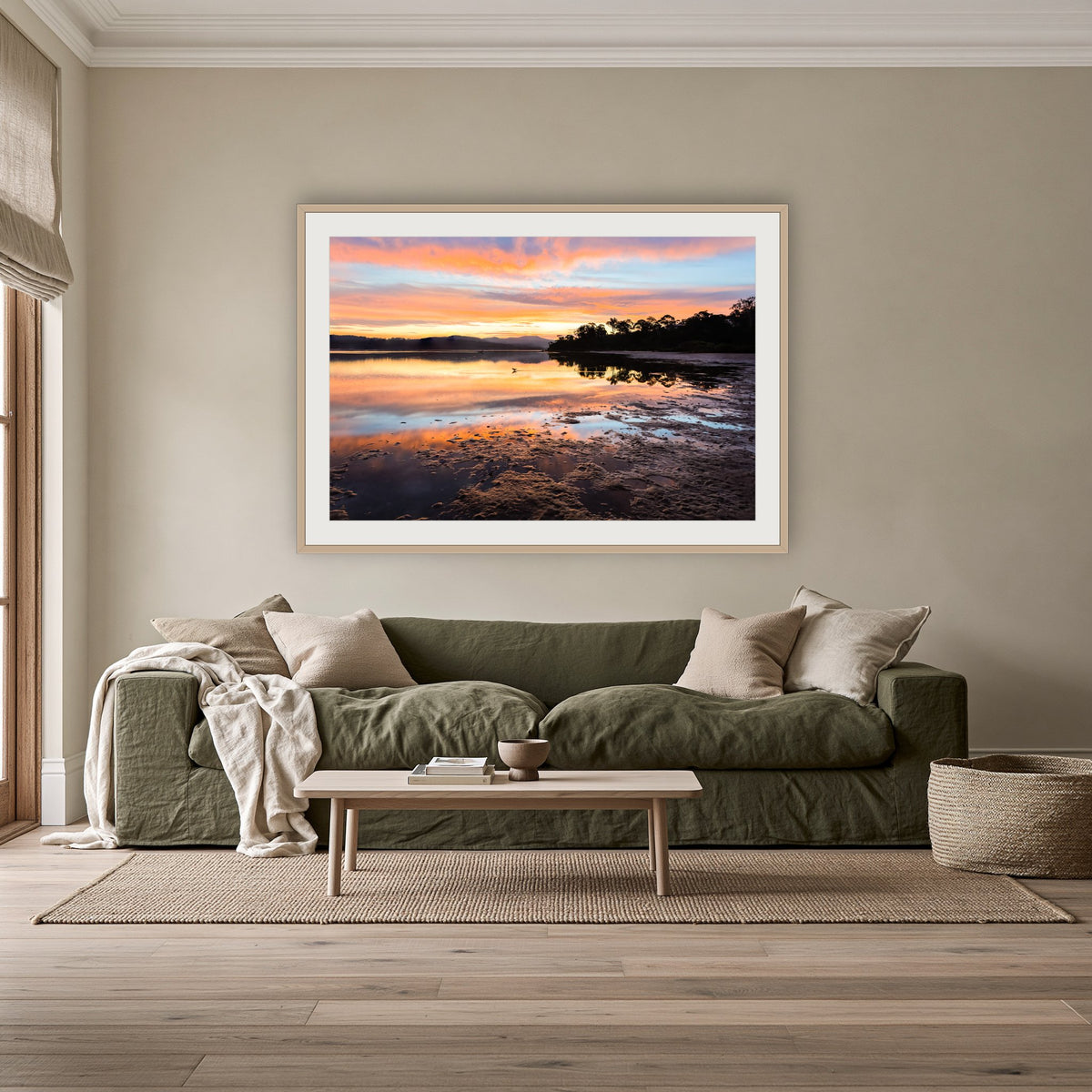 Top Lake Sunset framed print in oak with a white mat, above an olive linen sofa in a lounge room