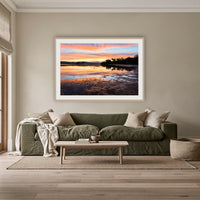 Top Lake Sunset framed print in oak with a white mat, above an olive linen sofa in a lounge room