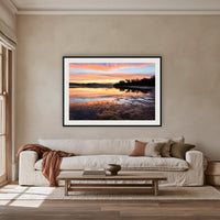 Top Lake Sunset framed print in black with a white mat, above an oatmeal linen sofa in a lounge room