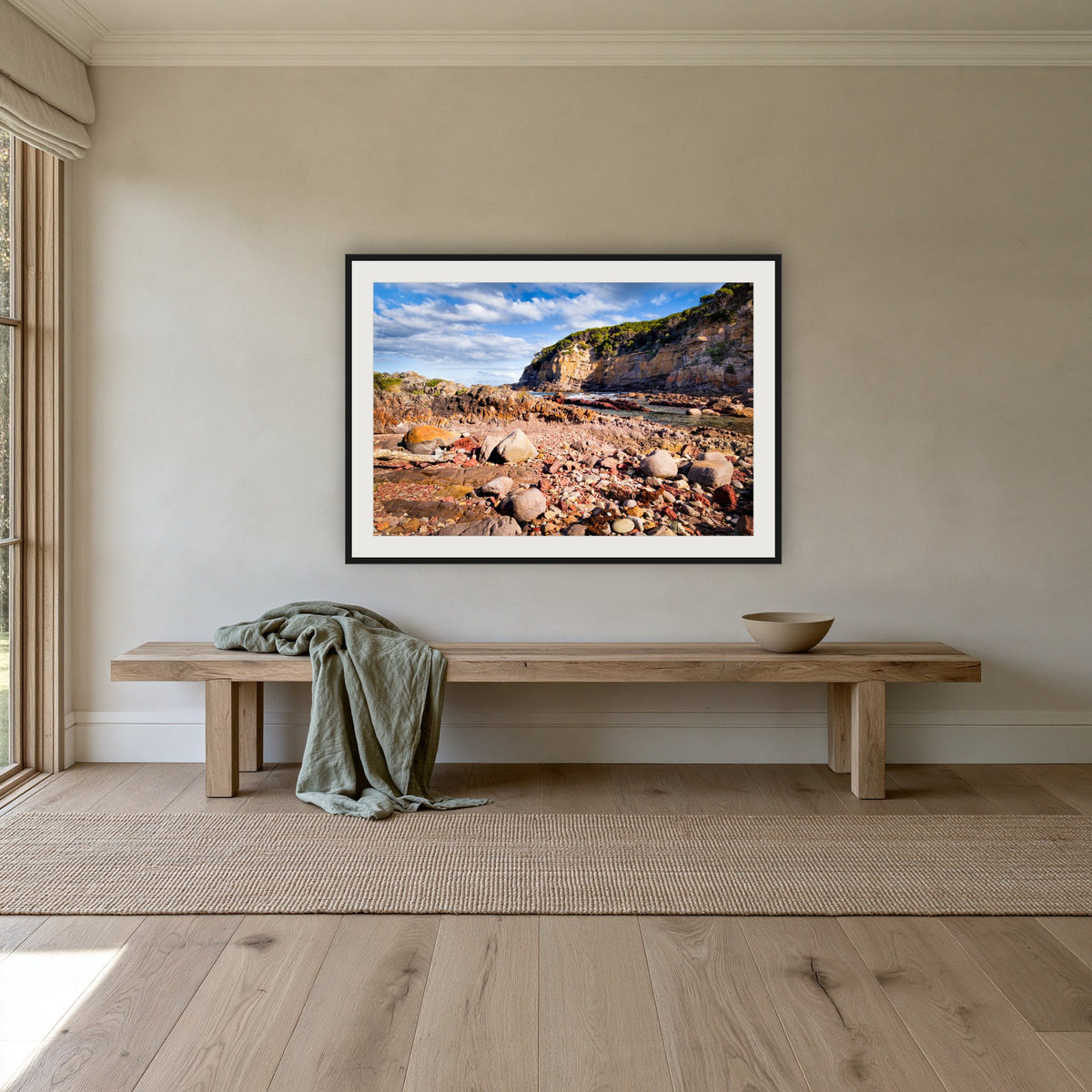 Lennards Island framed print in black with a white mat, above an oak bench in a hallway