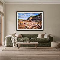 Lennards Island framed print in black with a white mat, above an olive linen sofa in a lounge room