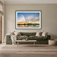 Rainbow over Merimbula Lake framed print in black with a white mat, above an olive linen sofa in a lounge room