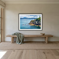 Twofold Bay Rocky Cliffs & Mt Imlay framed print in black with a white mat, above an oak bench in a hallway