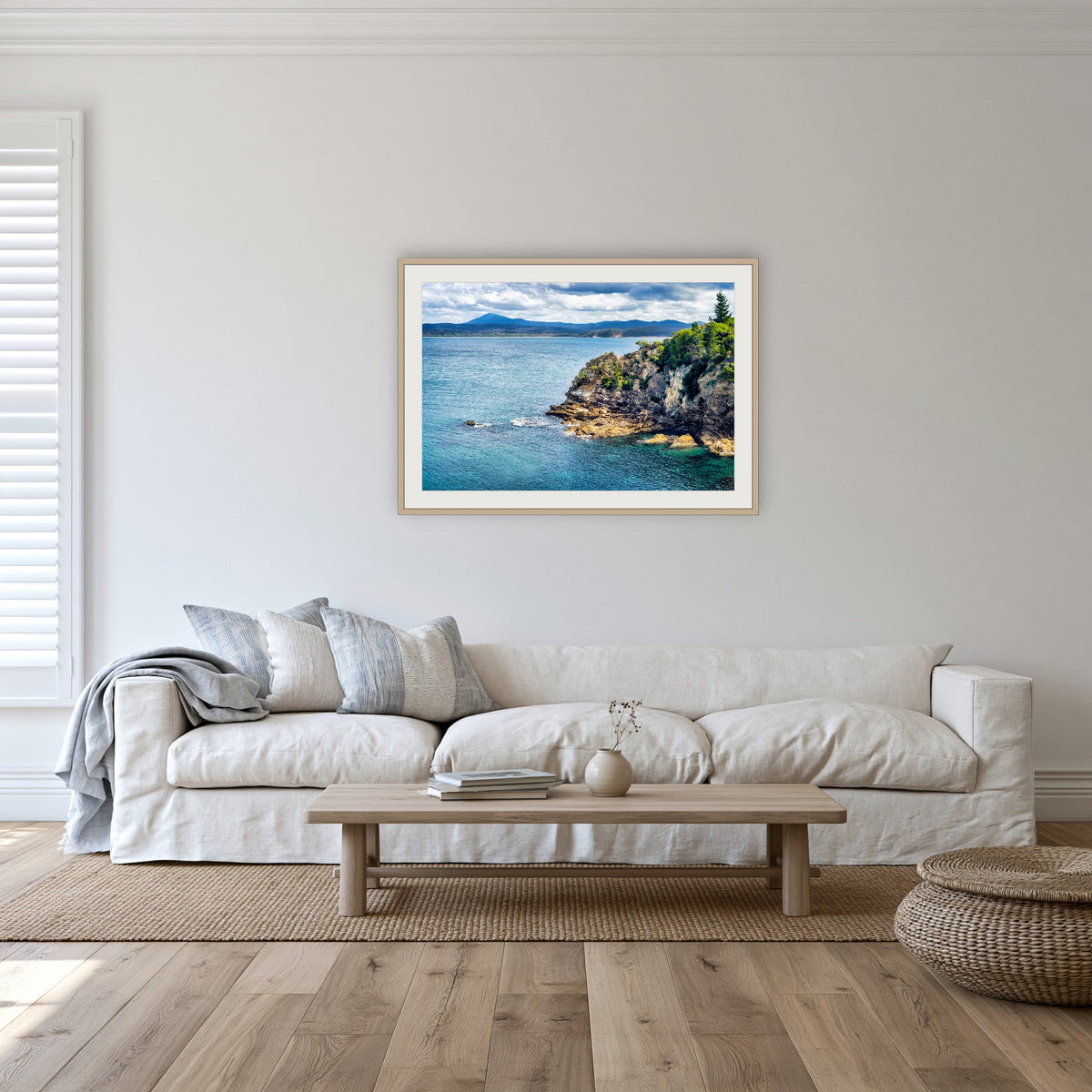 Twofold Bay Rocky Cliffs & Mt Imlay framed print in oak with a white mat, in a lounge room