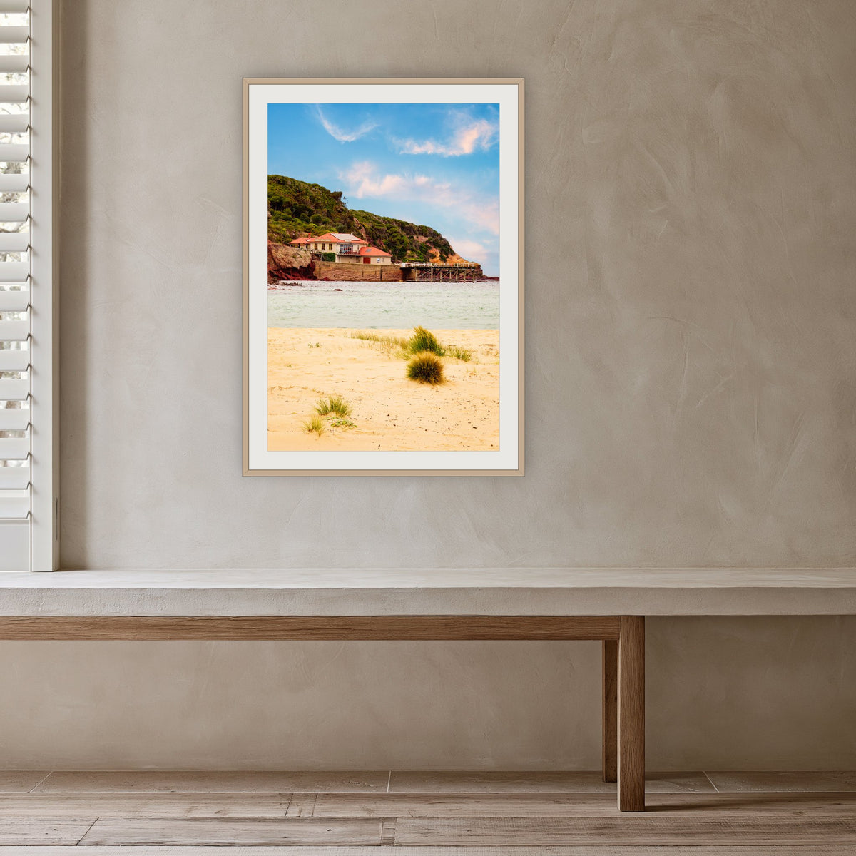 Merimbula Wharf from Main Beach framed print in oak with a white mat, in a plaster-walled hallway