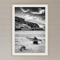 Merimbula Wharf from Main Beach in black and white, framed print in oak with a white mat, on a coastal lounge room wall