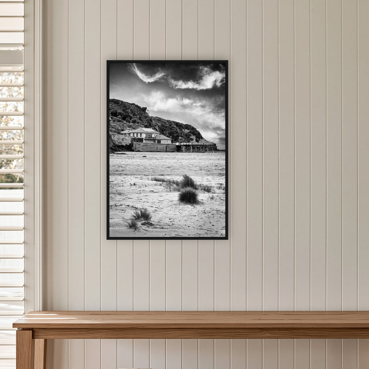Merimbula Wharf from Main Beach in black and white, in a black frame without a mat, on a panelled hallway wall