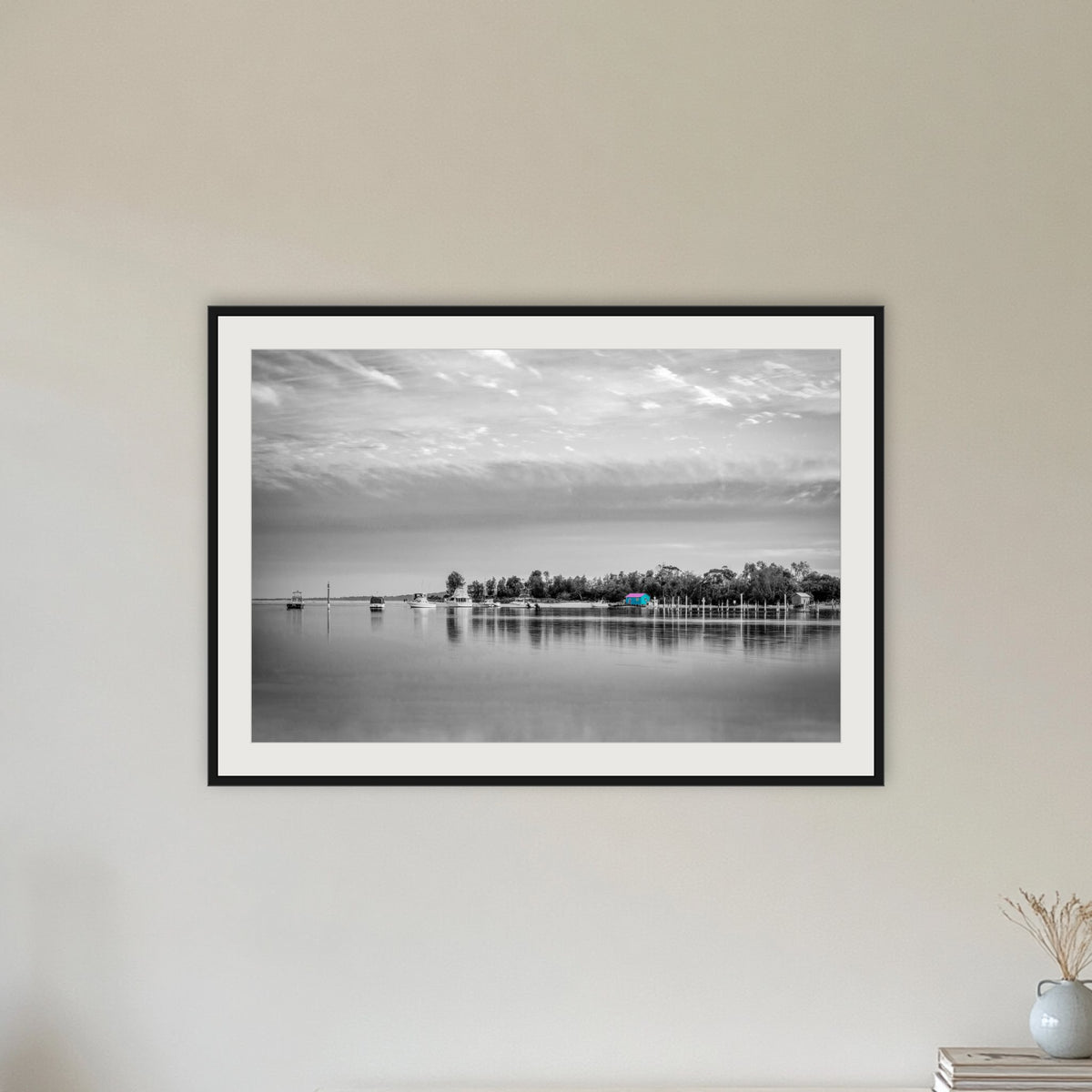 Mitchies Jetty in black and white with colour, framed print in black with a white mat, in a hallway