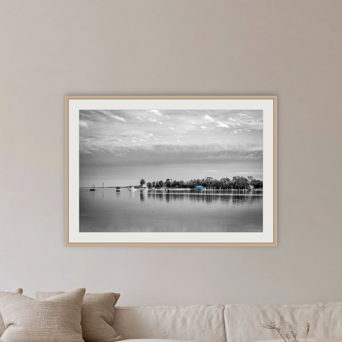 Mitchies Jetty in black and white with colour, framed print in oak with a white mat, in a lounge room