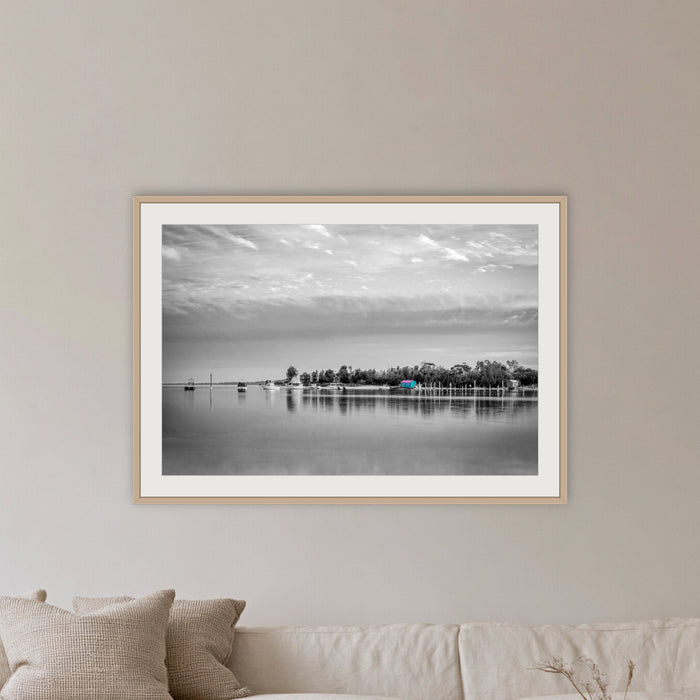 Mitchies Jetty in black and white with colour, framed print in oak with a white mat, in a lounge room