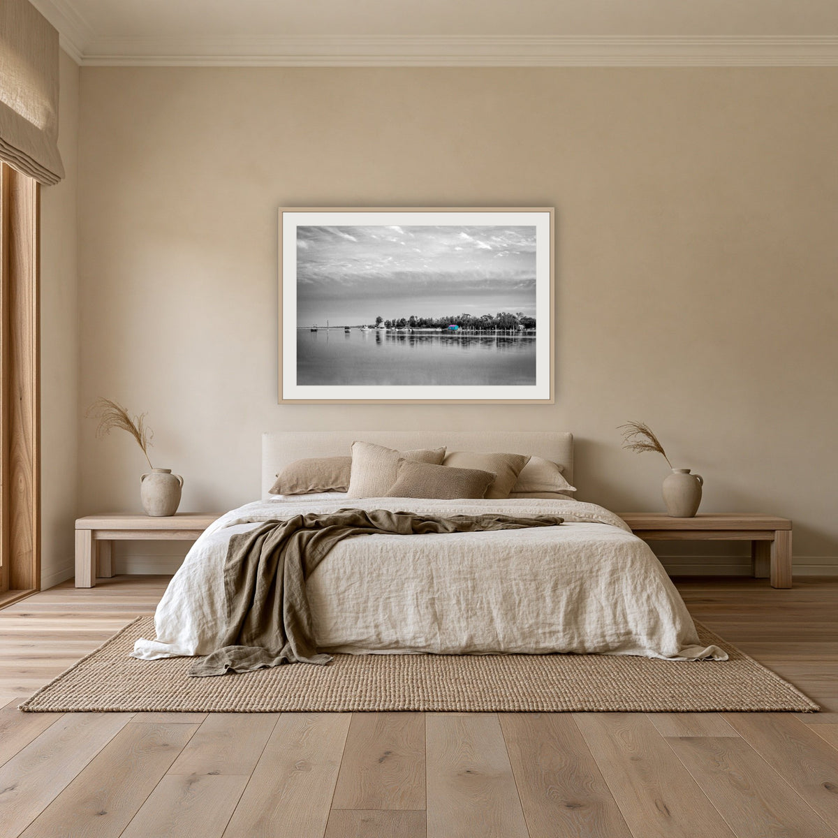 Mitchies Jetty in black and white with colour, framed print in oak with a white mat, above an oatmeal linen bed in a bedroom