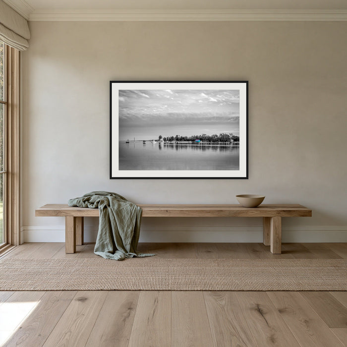 Mitchies Jetty in black and white with colour, framed print in black with a white mat, above an oak bench in a hallway