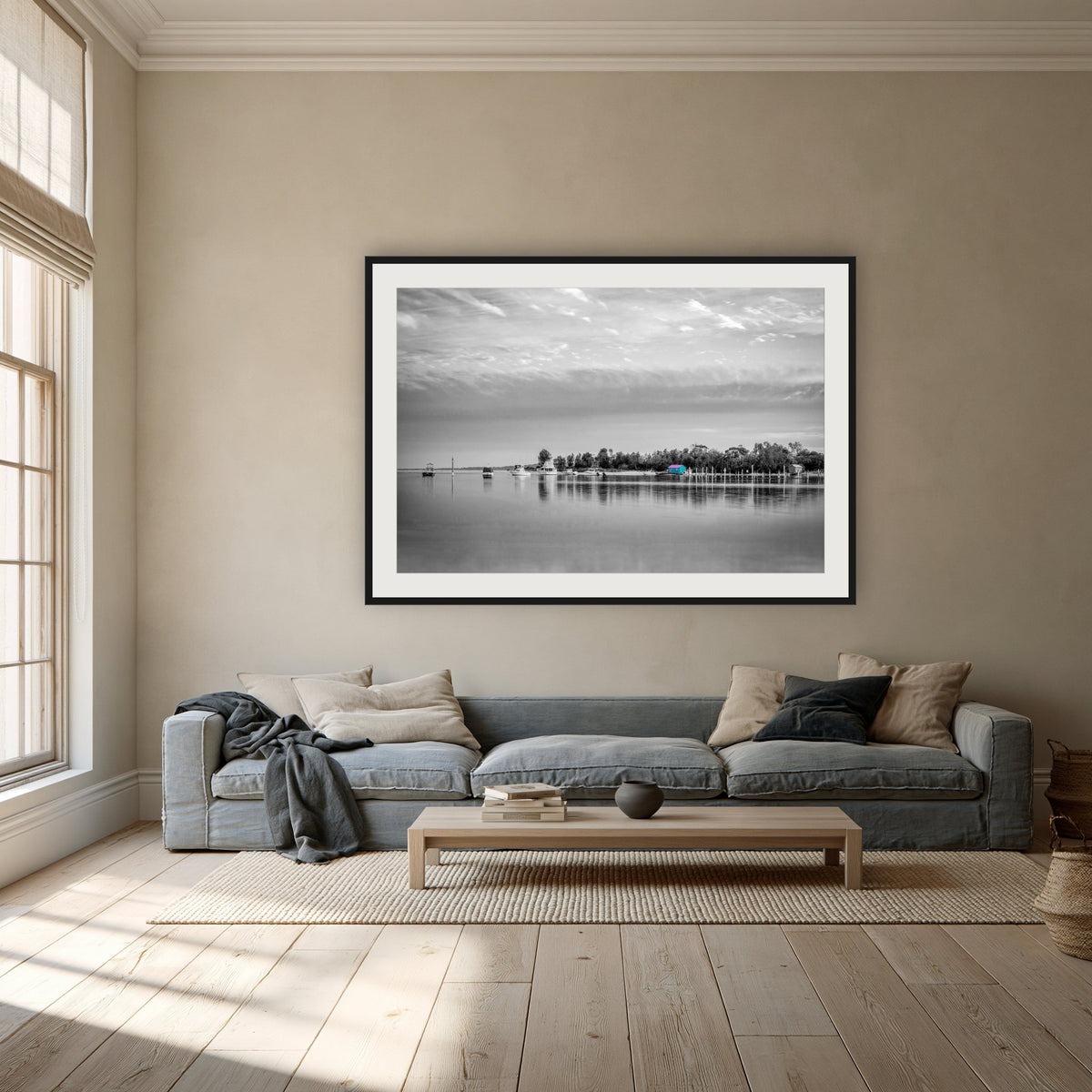Mitchies Jetty in black and white with colour, framed print in black with a white mat, above a dusty blue linen sofa in a lounge room