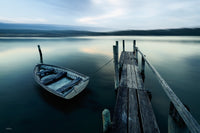 A wooden dinghy tied to a weathered jetty at dawn, the far shore rendered as soft abstract bands — fine art print