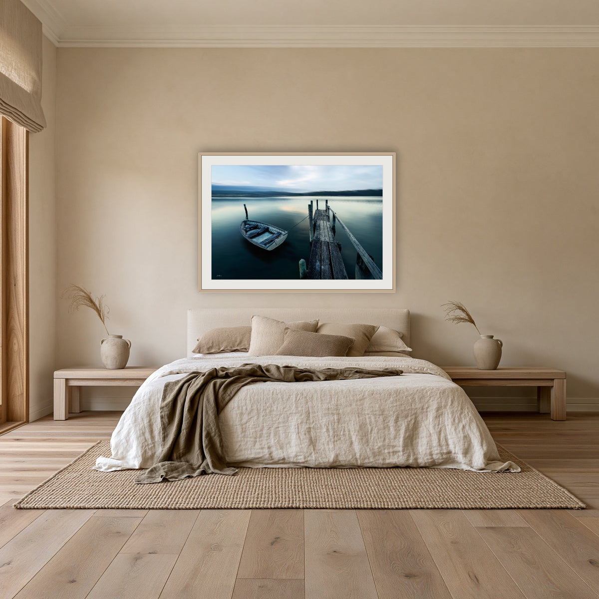 Little Boat at Fishpen Jetty framed print in oak with a white mat, above an oatmeal linen bed in a bedroom