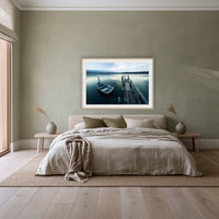 Little Boat at Fishpen Jetty framed print in oak with a white mat, above a linen bed against a sage wall in a bedroom