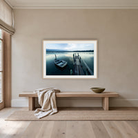 Little Boat at Fishpen Jetty framed print in oak with a white mat, above an oak bench in a hallway