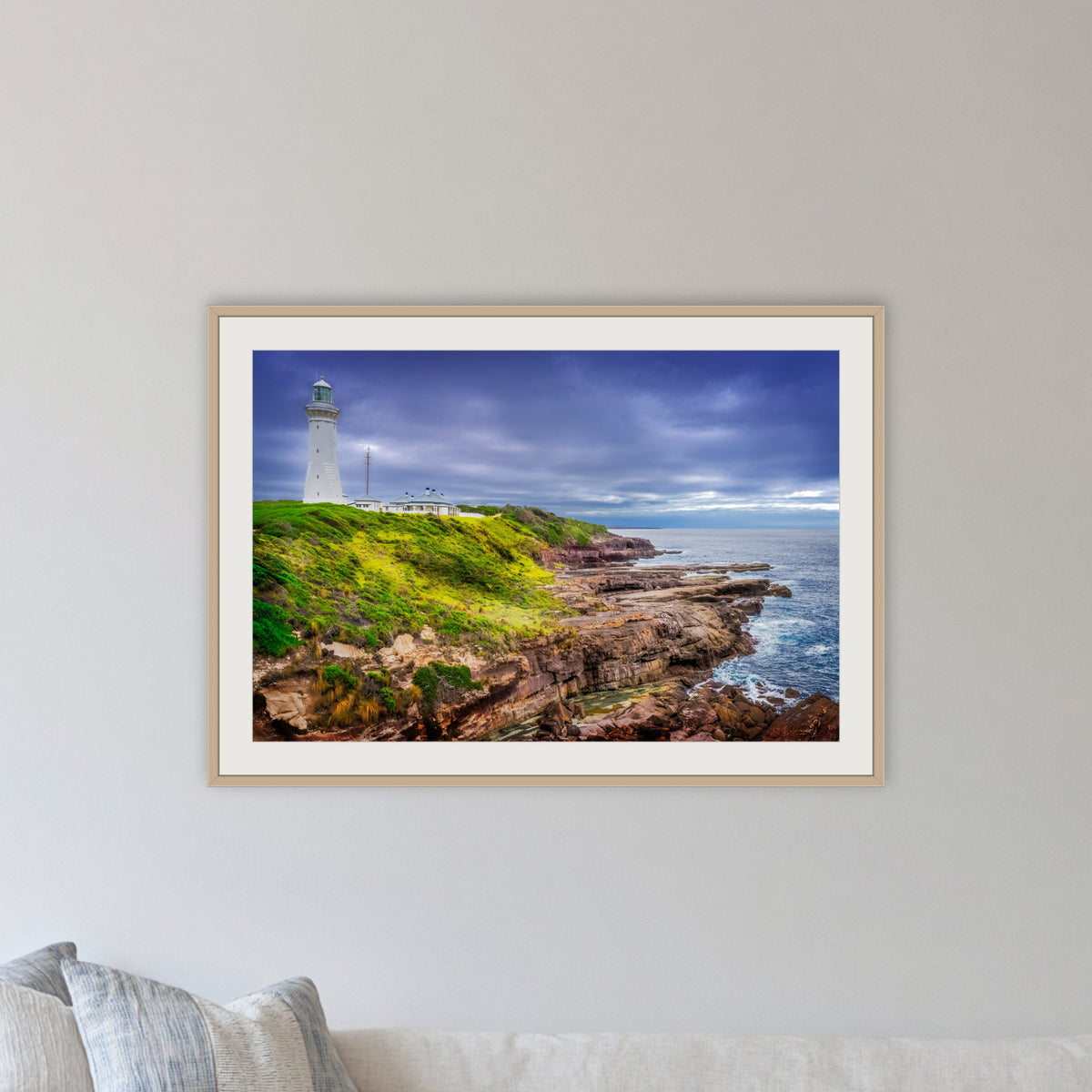 Green Cape Lighthouse framed print in oak with a white mat, in a lounge room