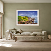 Green Cape Lighthouse framed print in oak with a white mat, above a linen sofa against a sage wall in a lounge room