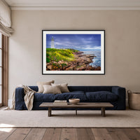 Green Cape Lighthouse framed print in black with a white mat, above a navy linen sofa in a lounge room