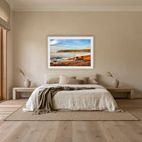 Short Point Sunrise framed print in oak with a white mat, above an oatmeal linen bed in a bedroom