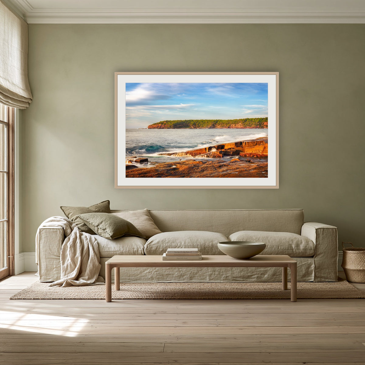 Short Point Sunrise framed print in oak with a white mat, above a linen sofa against a sage wall in a lounge room