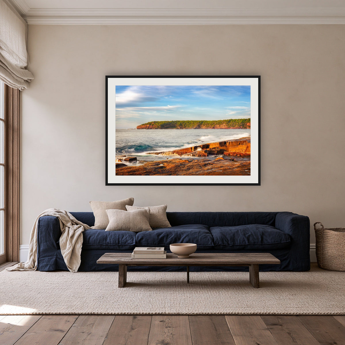 Short Point Sunrise framed print in black with a white mat, above a navy linen sofa in a lounge room