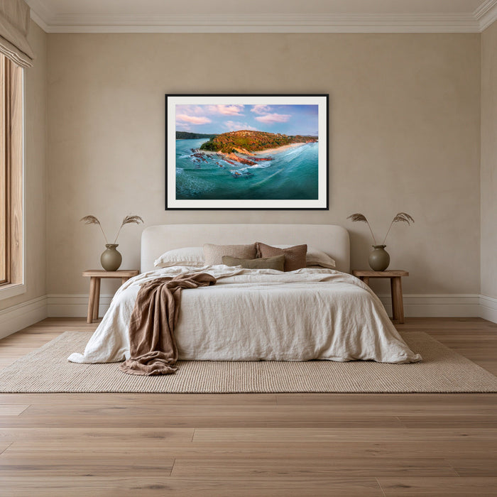 Pambula Beach Seascape framed print in black with a white mat, above an ivory linen bed in a bedroom