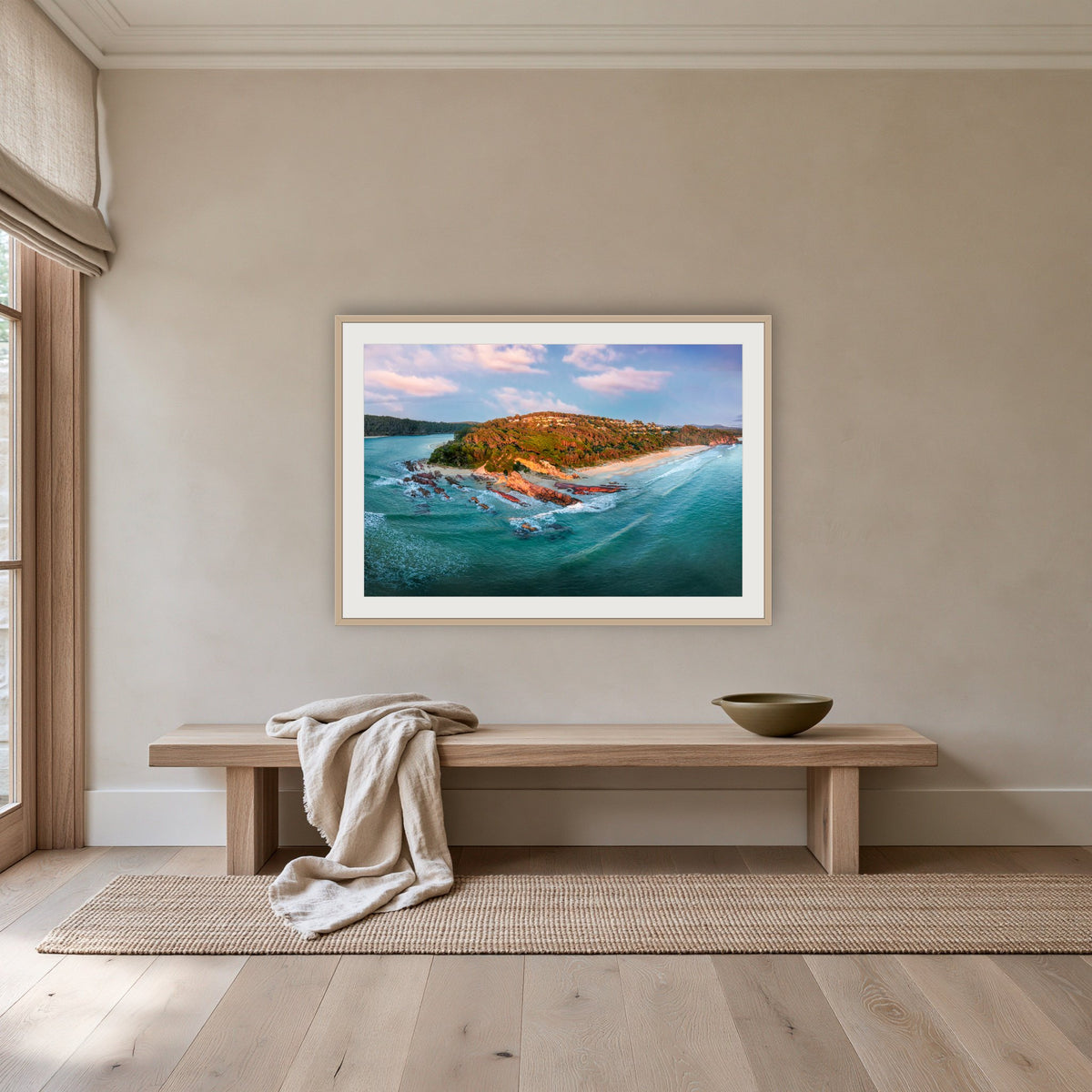 Pambula Beach Seascape framed print in oak with a white mat, above an oak bench in a hallway