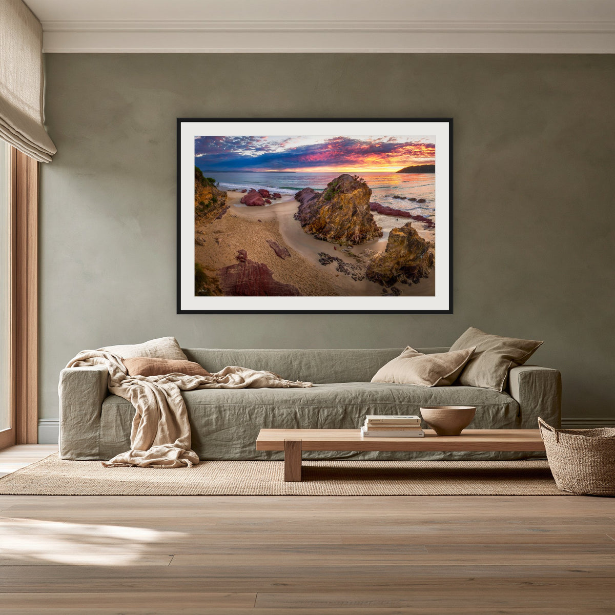 Pambula Beach Sunrise framed print in black with a white mat, above a sage linen sofa in a lounge room