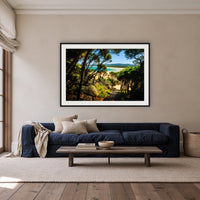 Wallagoot Lake framed print in black with a white mat, above a navy linen sofa in a lounge room
