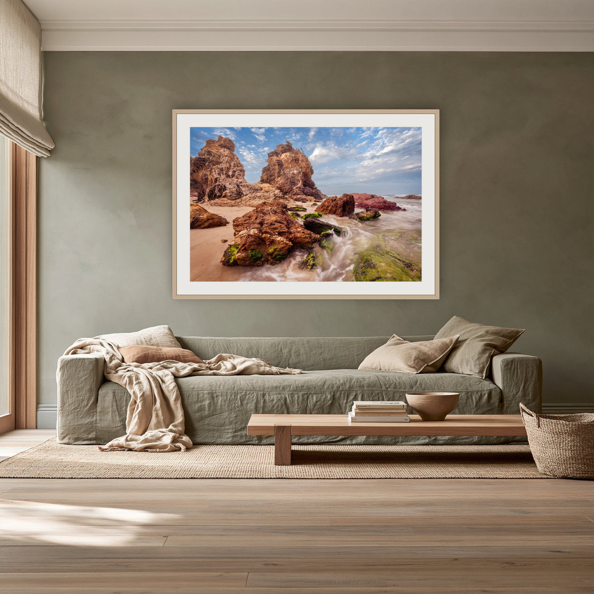 Pambula Rocks framed print in oak with a white mat, above a sage linen sofa in a lounge room