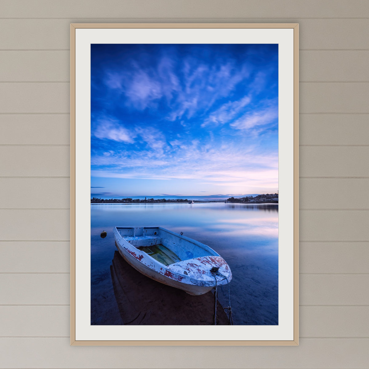 Little Dinghy on Merimbula Lake framed print in oak with a white mat, in a coastal lounge room