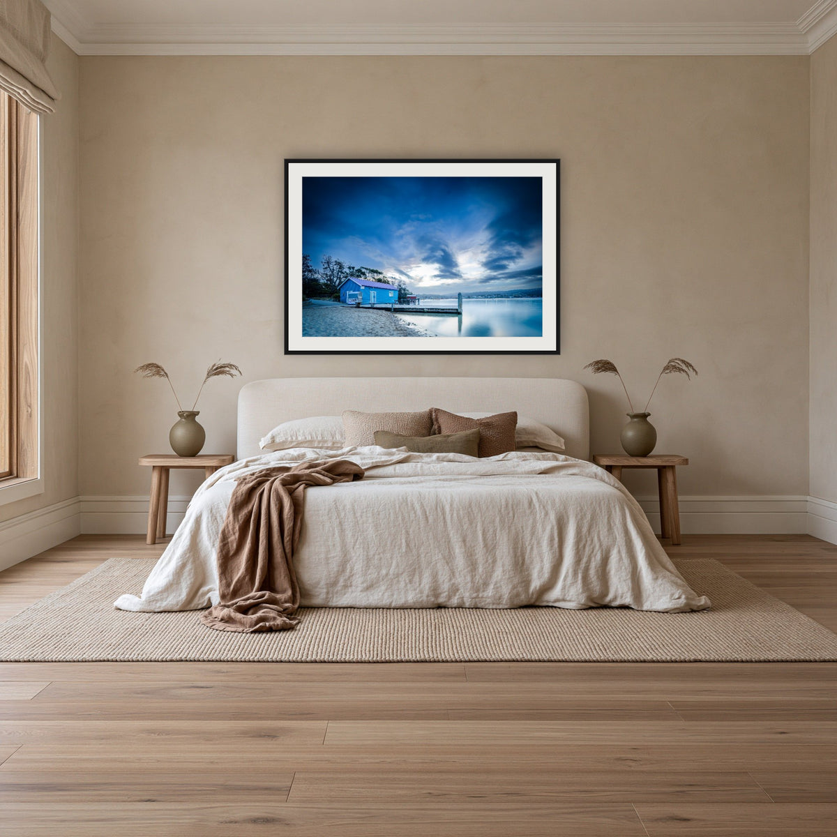 Mitchies Jetty at Dusk framed print in black with a white mat, above an ivory linen bed in a bedroom