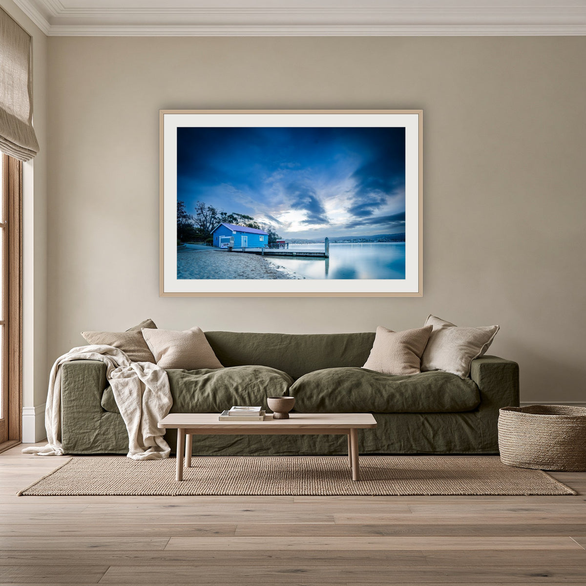 Mitchies Jetty at Dusk, Smooth Lake framed print in oak with a white mat, above an olive linen sofa in a lounge room