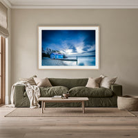 Mitchies Jetty at Dusk, Smooth Lake framed print in oak with a white mat, above an olive linen sofa in a lounge room
