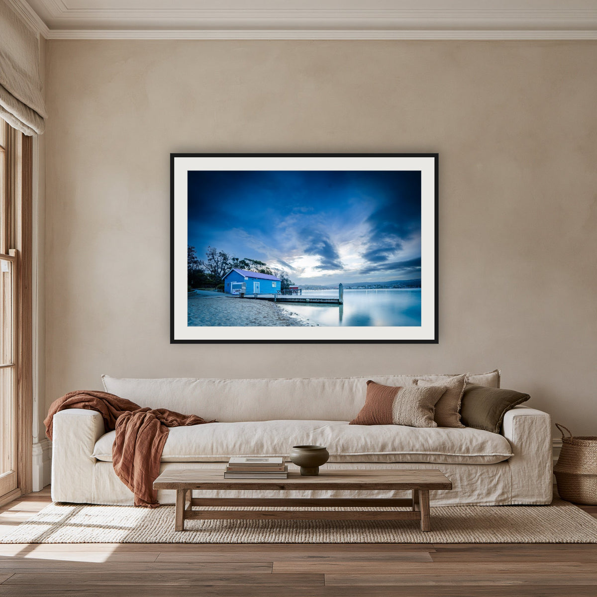Mitchies Jetty at Dusk, Smooth Lake framed print in black with a white mat, above an oatmeal linen sofa in a lounge room