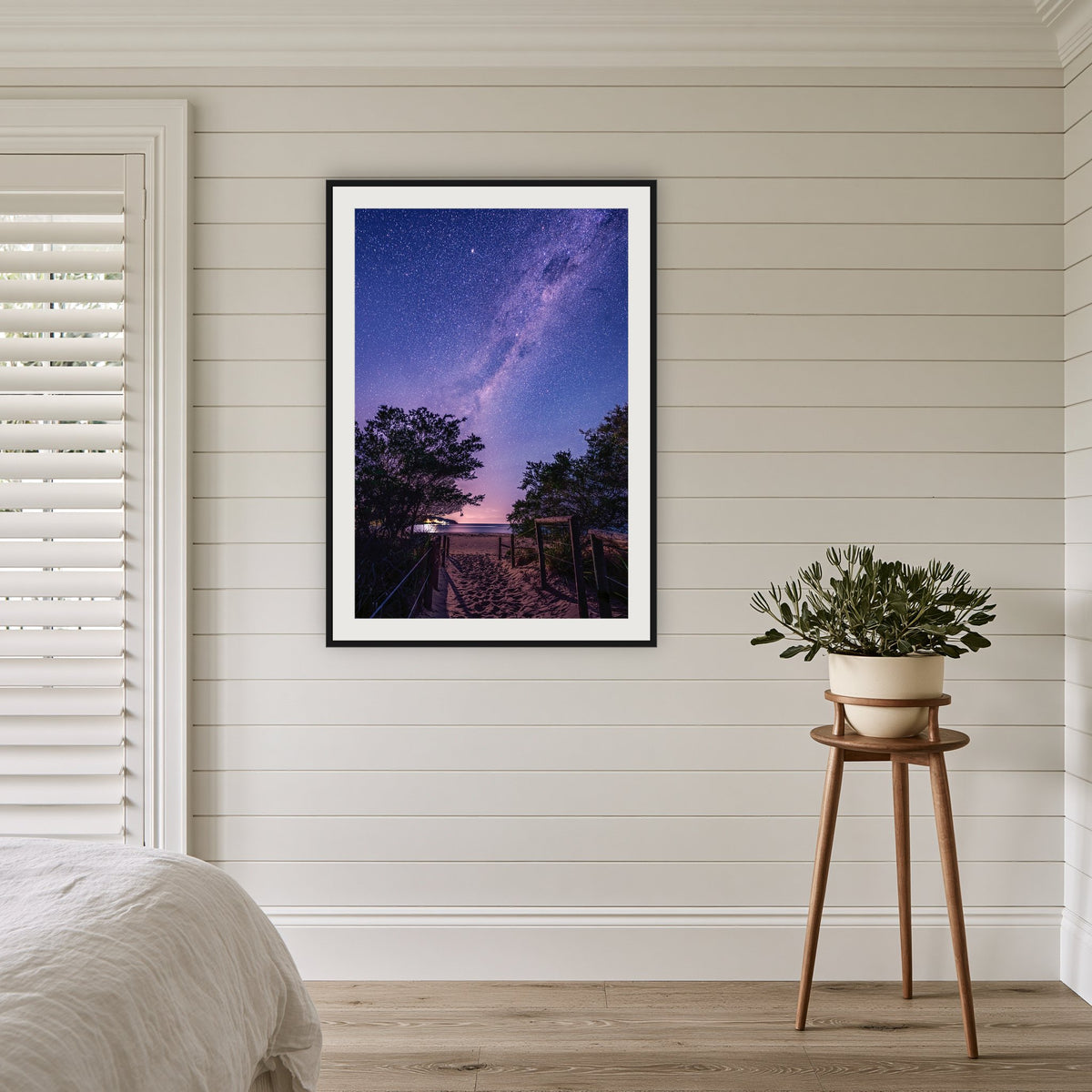 Main Beach Milky Way framed print in black with a white mat, in a coastal bedroom