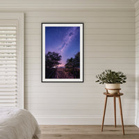 Main Beach Milky Way framed print in black with a white mat, in a coastal bedroom