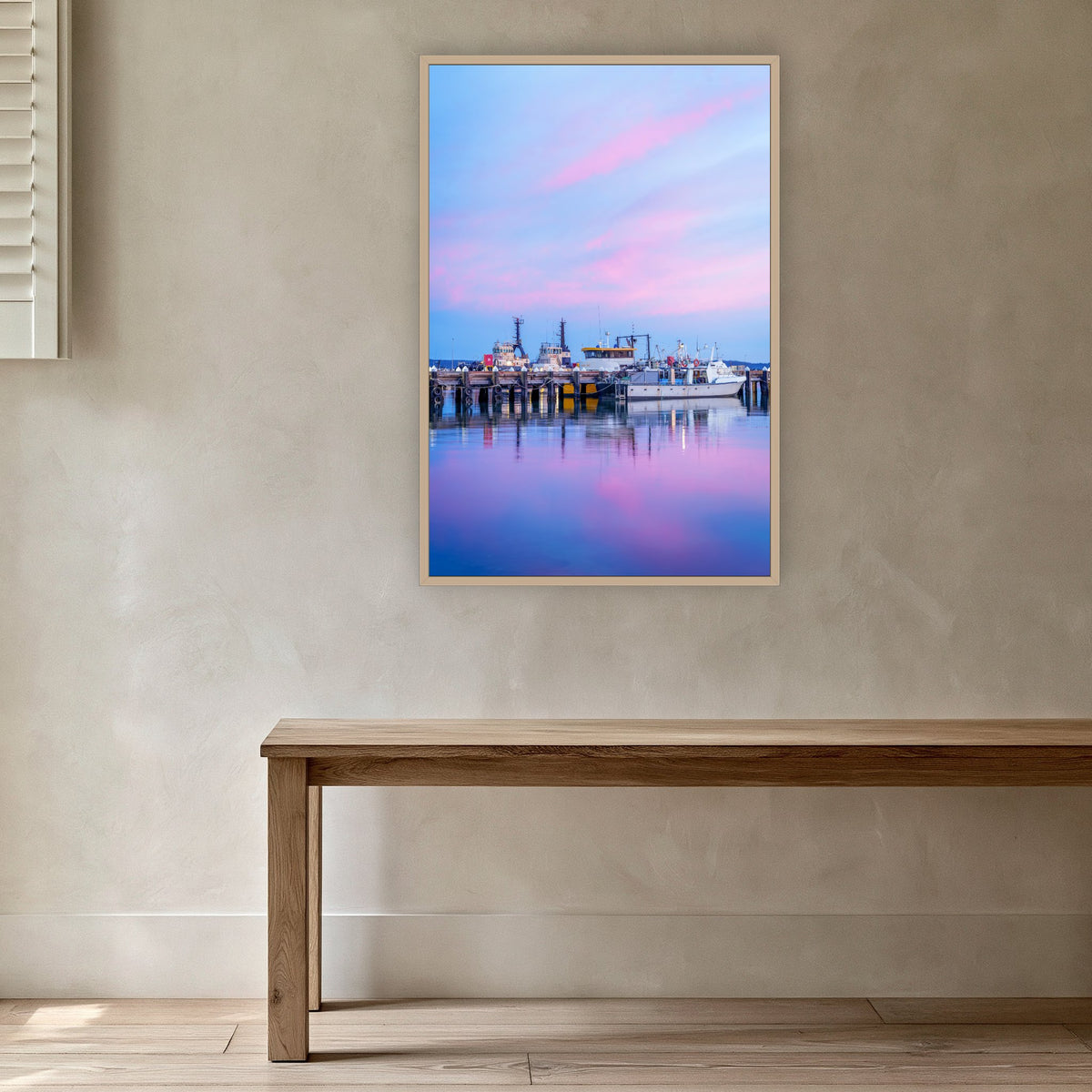 Eden Wharf Tugs in an oak frame without a mat, in a plaster-walled hallway