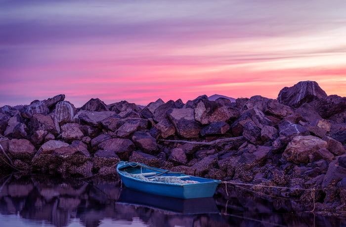 A lone blue dinghy against the Eden breakwall at last light, Twofold Bay, Eden NSW — fine art print