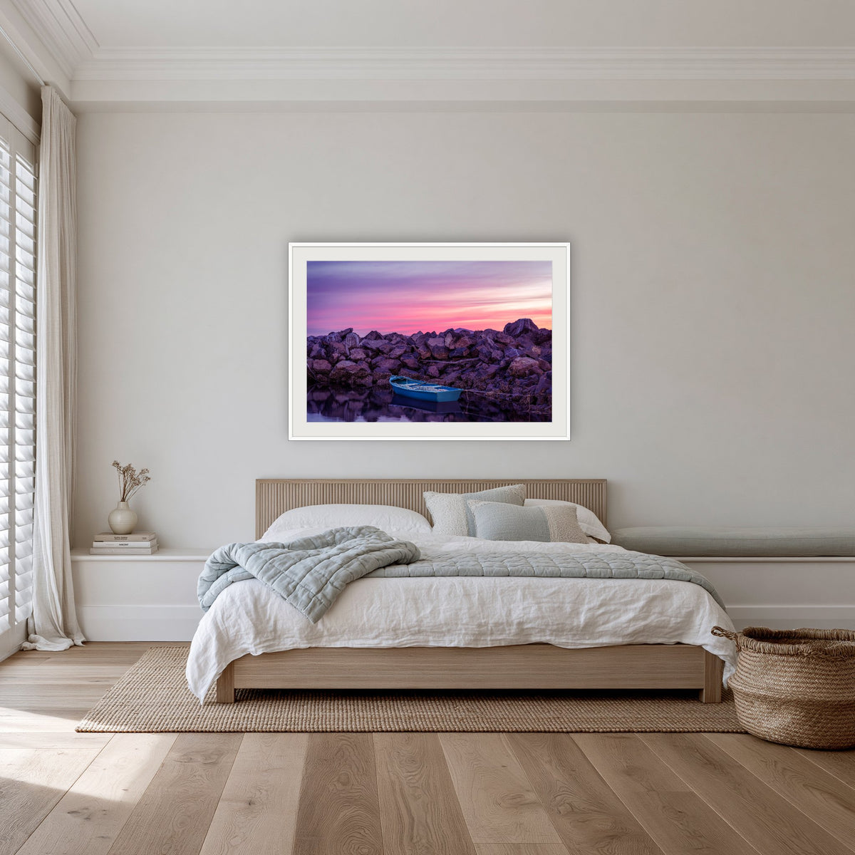 Eden Twofold Hush wall art — a lone blue dinghy against the Eden breakwall at last light, shown in a white frame with a mat in a bedroom