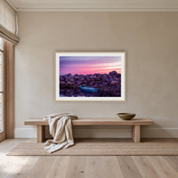 Eden Twofold Hush wall art — a lone blue dinghy against the Eden breakwall at last light, shown in an oak frame with a white mat above an oak bench in a hallway