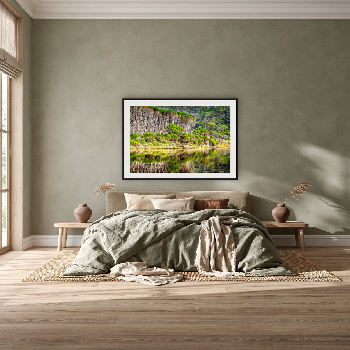 Bournda Lagoon's Serenity framed print in black with a white mat, above a khaki linen bed against a green-grey wall in a bedroom