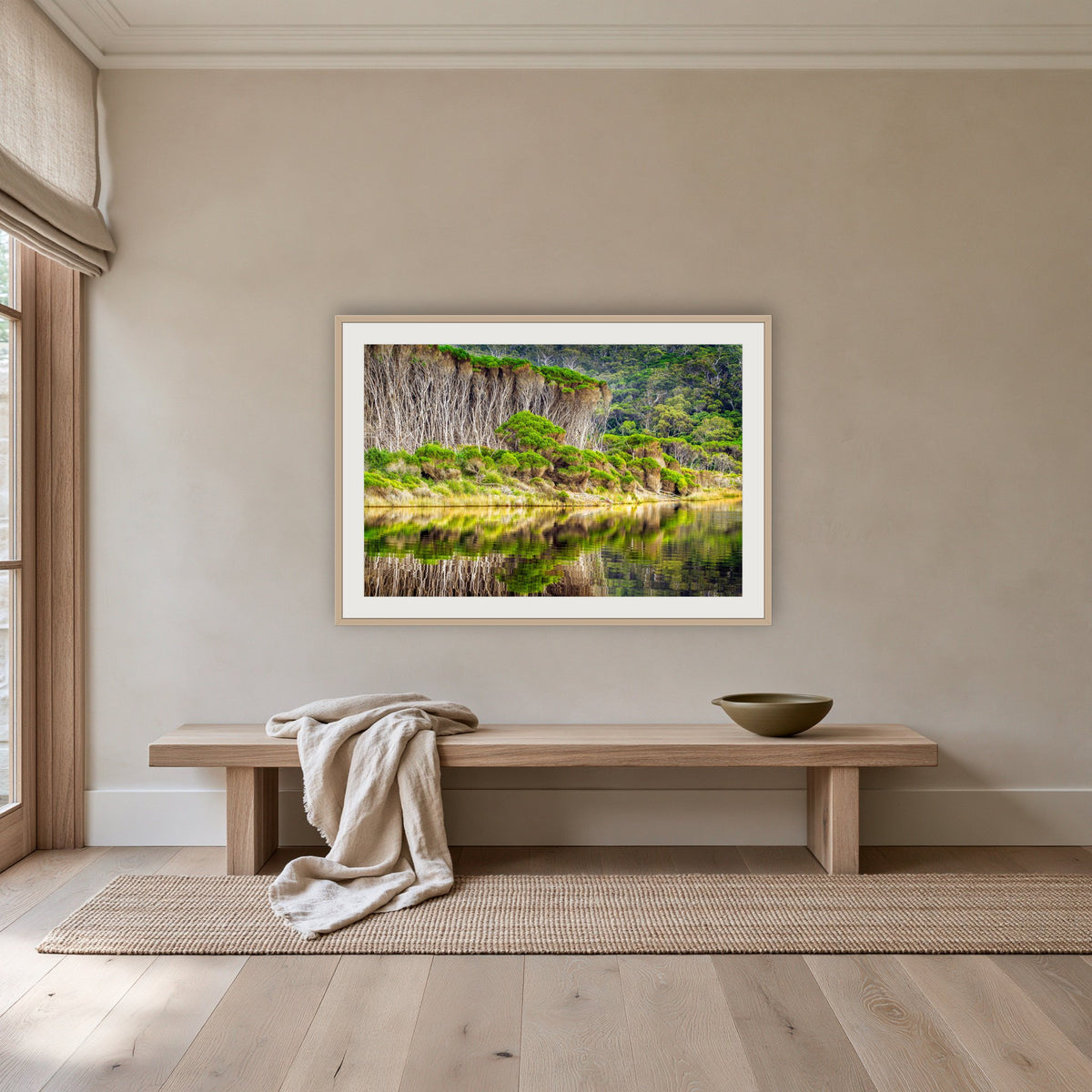Bournda Lagoon's Serenity framed print in oak with a white mat, above an oak bench in a hallway